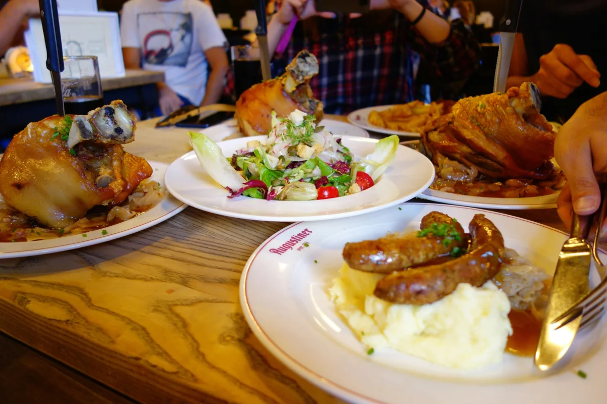 Roasted pork knuckles, sausages with sauerkraut, and mashed potatoes on a German tavern table